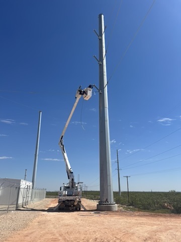 KTX bucket truck working on a tall steel utility pole