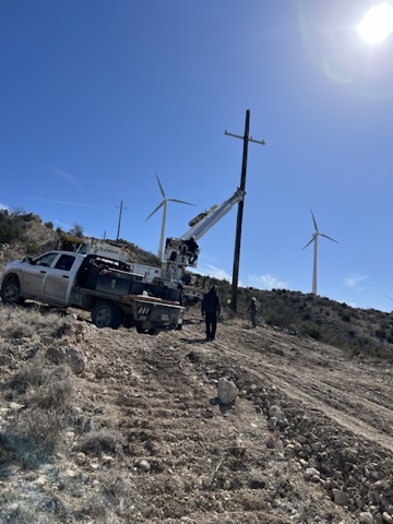 KTX crew and bucket truck performing line work in hilly terrain